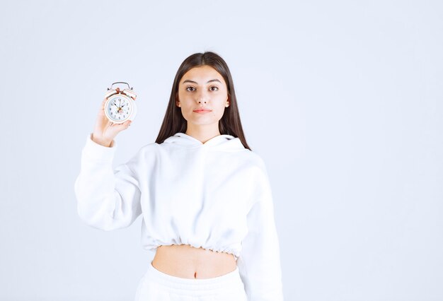 cute young girl model holding an alarm clock.