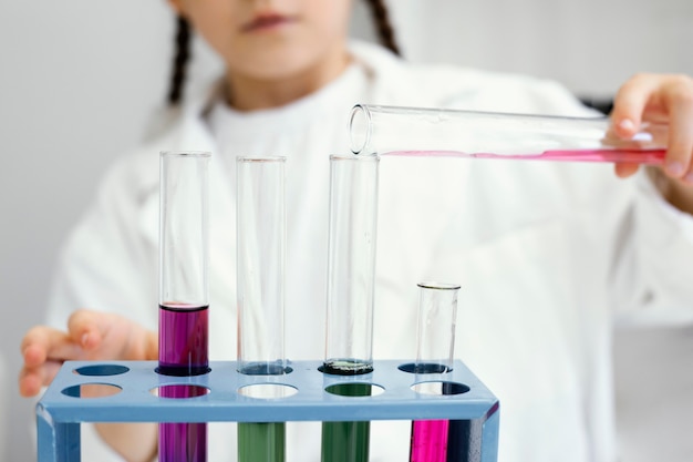 Cute young girl scientist doing experiments with test tubes