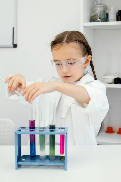 Cute young girl scientist with test tubes doing experiments