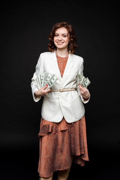 Cute young girl shows a lot of money in the hands, picture isolated on black space