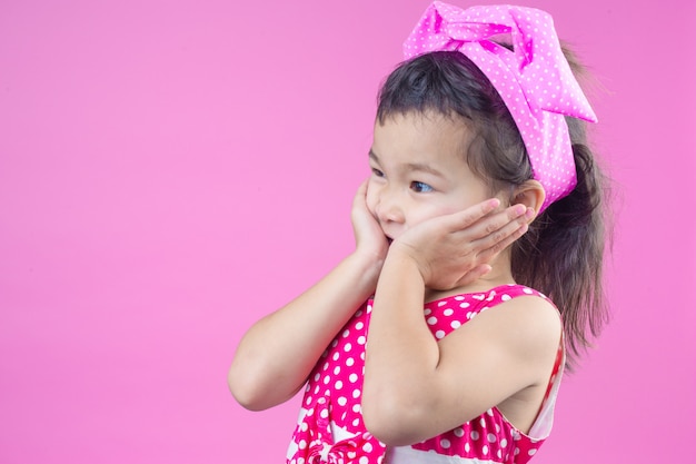 赤い縞模様のシャツを着ているかわいい若い女の子は、頭とピンクのピンクの弓を結びました。