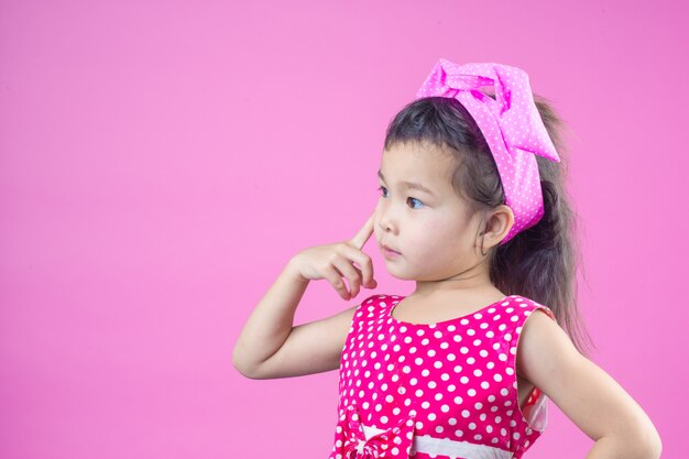 Cute young girl wearing a red striped shirt, tied a pink bow on the head and pink .