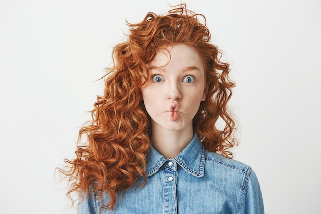 Cute young girl with foxy curly hair making funny face . Copy space.