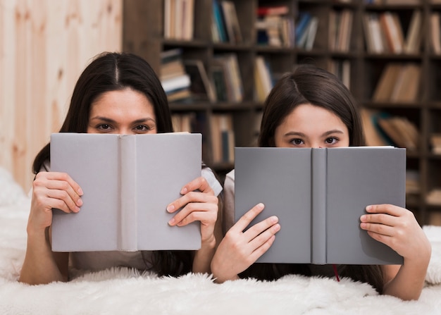 Volti svegli della copertura della donna e della ragazza con i libri