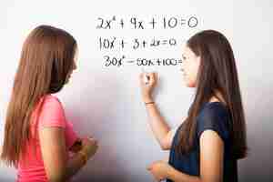 Foto gratuita giovani studenti delle scuole superiori svegli che risolvono alcune equazioni di algebra su una lavagna bianca