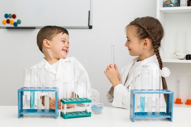 Cute young kids scientists with test tubes and lab coats