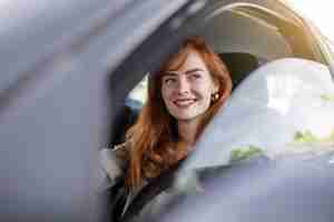 Free photo cute young lady happy driving car image of beautiful young woman driving a car and smiling portrait of happy female driver steering car with safety belt