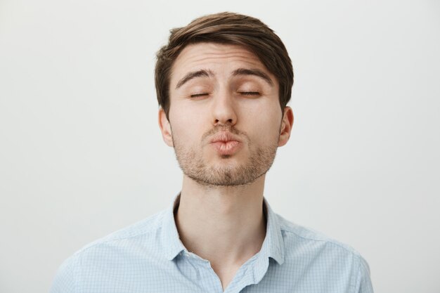 Cute young man with bristtle close eyes as waiting for kiss