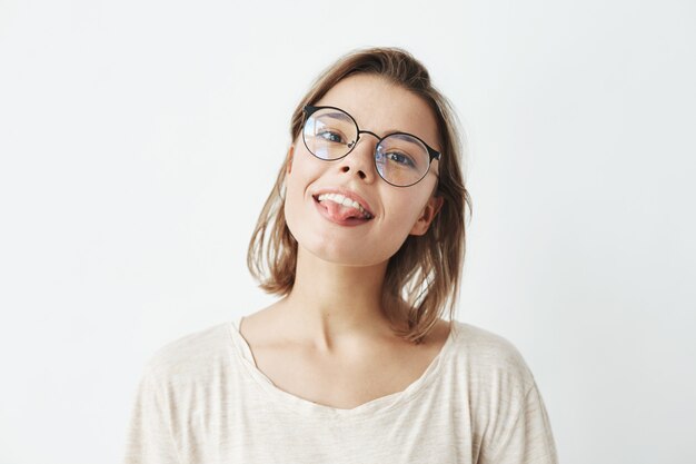 Cute young pretty girl in glasses smiling showing tongue .