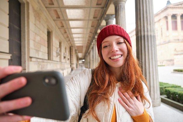 かわいい若い赤毛の女性は、携帯電話で路上でセルフィーを撮り、smar で自分の写真を撮ります