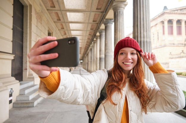 Carina giovane donna rossa prende selfie in strada con il cellulare fa una foto di se stessa con smar