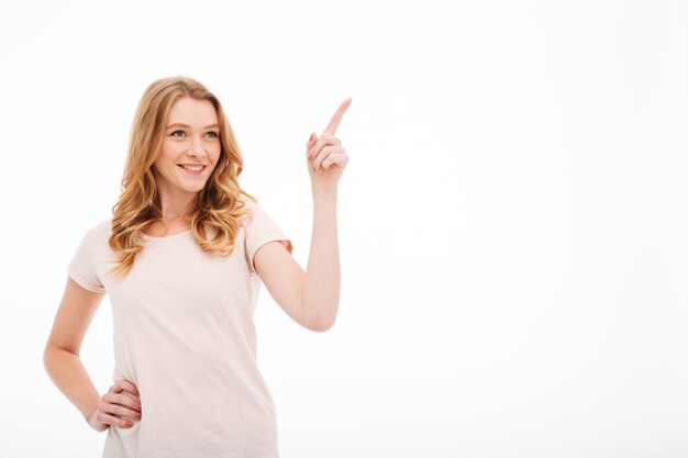 Cute young smiling lady pointing.