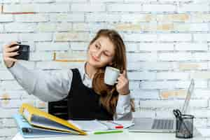 Free photo cute young student sitting on white background and on the phone high quality photo