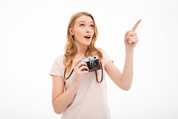 Cute young woman holding camera pointing.