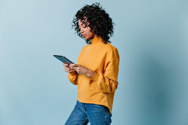 Cute young woman in jeans using digital tablet