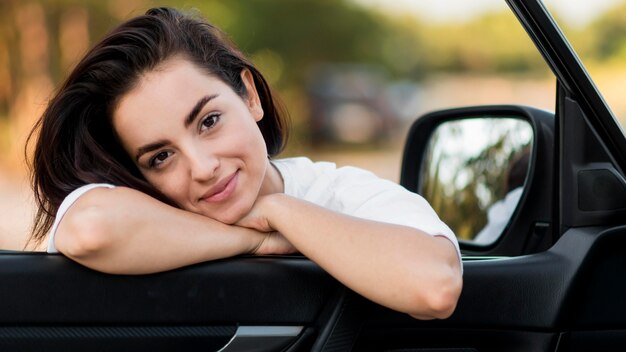 cute young woman leaning on a car door