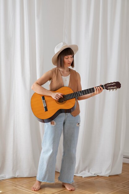 Cute young woman playing guitar indoors