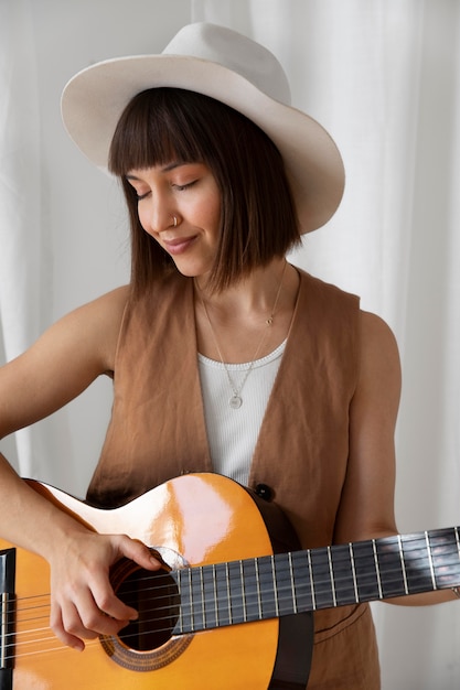 Cute young woman playing guitar indoors