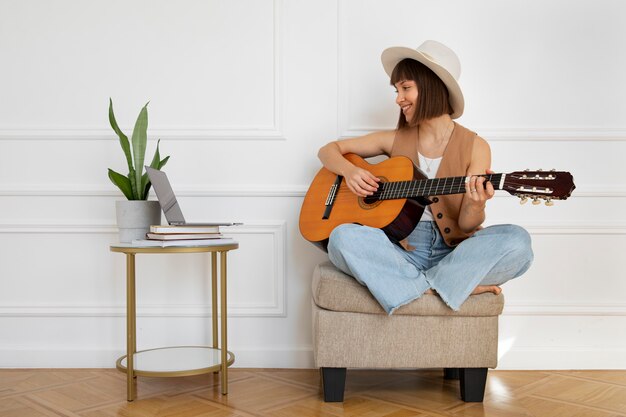 Милая молодая женщина играет на гитаре в помещении