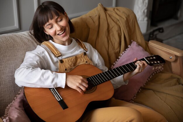 Cute young woman playing guitar indoors