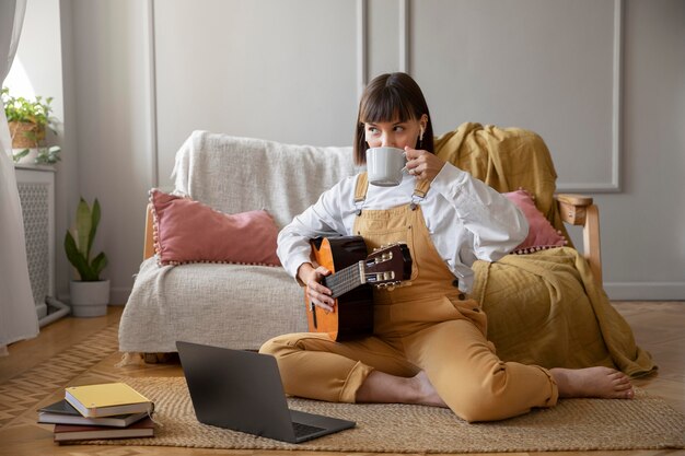 屋内でギターを弾くかわいい若い女性