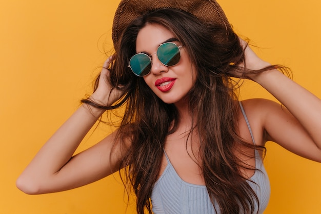 Cute young woman posing wit gently smile, standing with hands up on yellow space