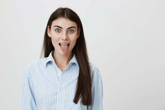Cute young woman showing tongue, smiling