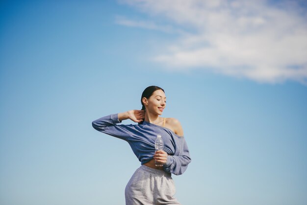 Cute young woman training with bottle of water