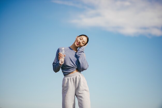 水のボトルとトレーニングかわいい若い女性