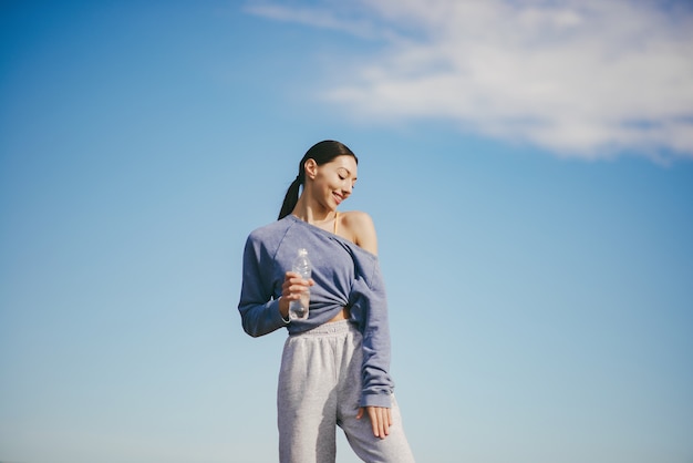 Free photo cute young woman training with bottle of water