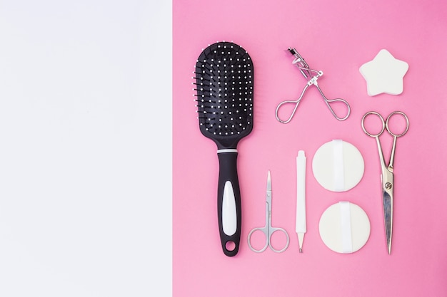 Cuticle; hair brush; scissors; sponge; eyelash curler and sponge on pink backdrop