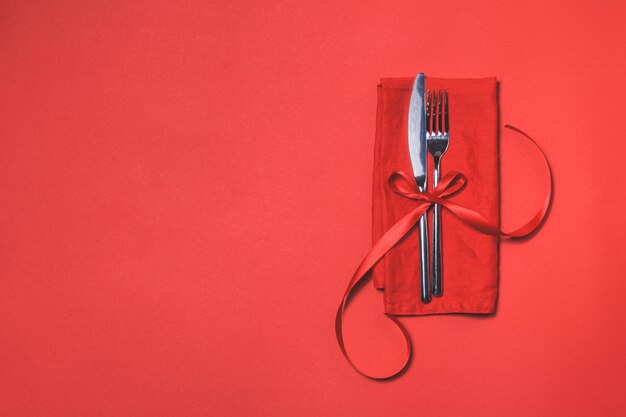 Cutlery tied with a red bow on a red napkin