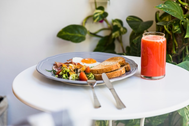 Free photo cutlery with gray plate of breakfast and smoothies on round white table