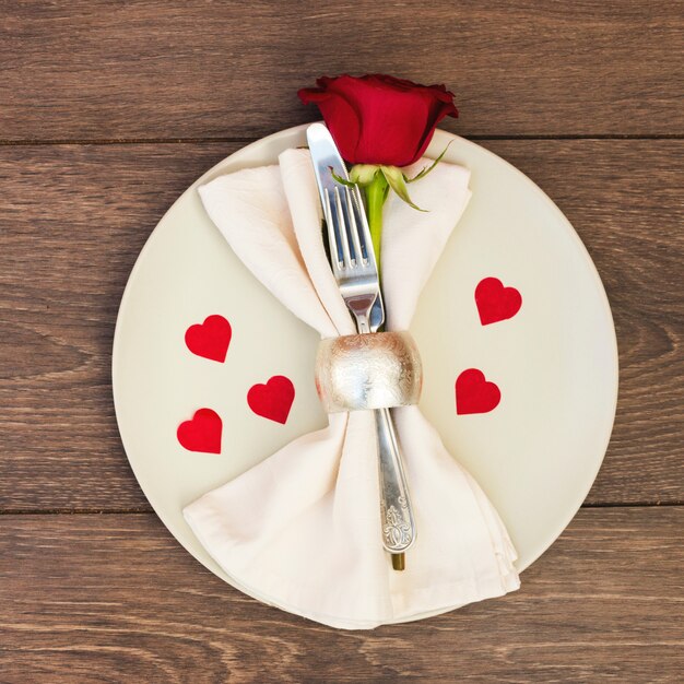 Cutlery with napkin and flower on plate 