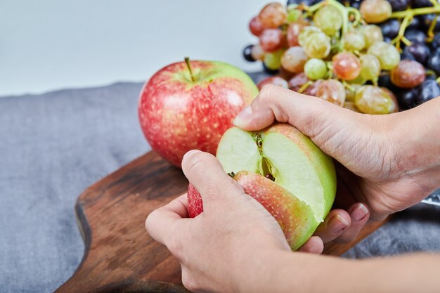 Cutting an apple into two halves and bunch of grapes on a wooden board. High quality photo