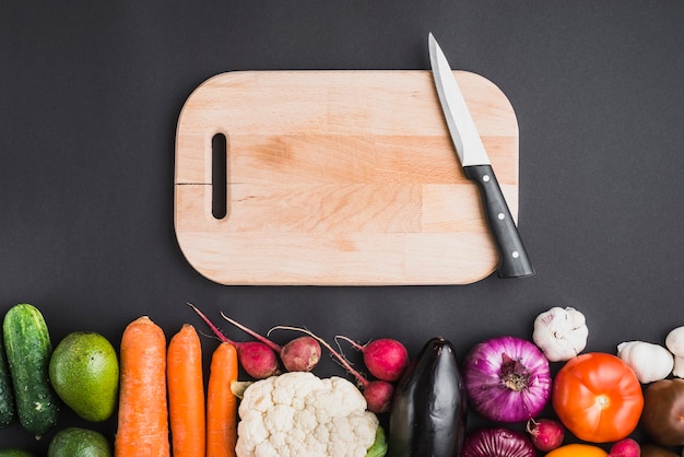 Cutting board and knife near vegetables