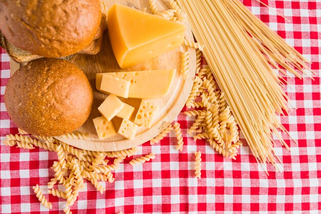 新鮮なチーズとパンとテーブルの上に散らばったパスタのまな板
