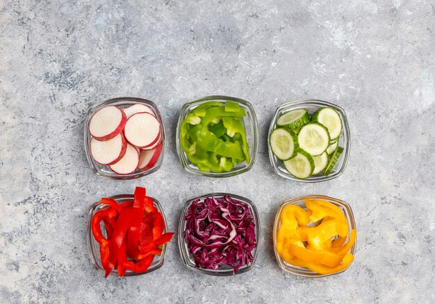 Cutting board with slices of colorful bell peppers on light surface. Sliced sweet peppers in different colors, vegetable salad ingredient, cooking healthy food, top view