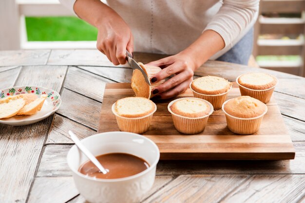 Cutting cupcake and bowl of filling