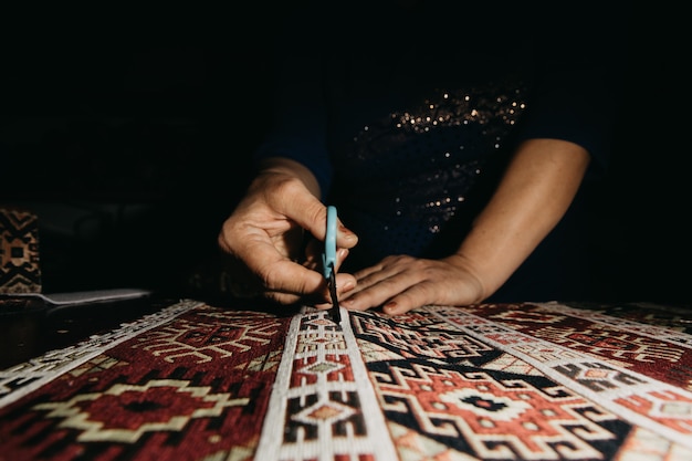 Cutting ethnic carpet with scissors