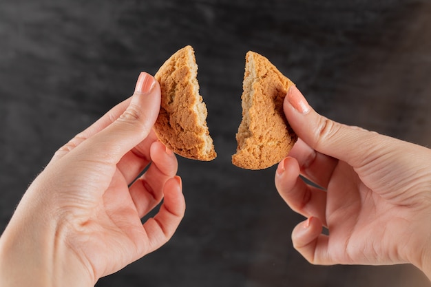 Cutting an oatmeal cookie in the hand into two pieces.