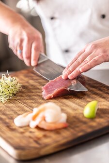 まな板の上でプロの寿司職人が生のマグロを切る。
