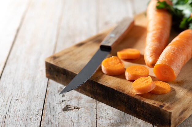 Cutting raw carrots on wooden table