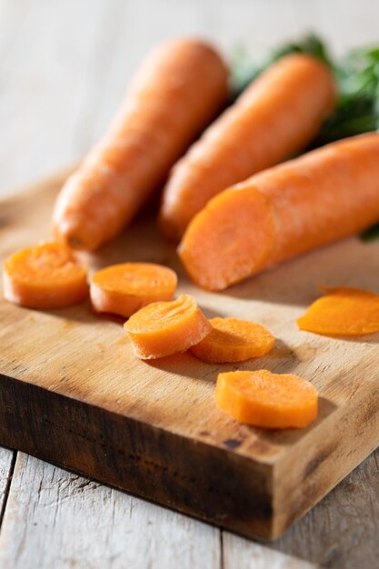 Cutting raw carrots on wooden table