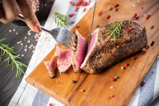 Cutting roasted beef sirloin with rosemary and pepper