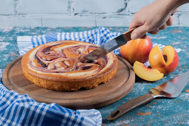 Cutting a slice of chocolate syrup pie on a wooden board. 