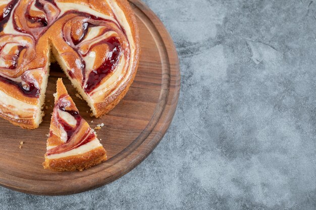 Cutting a slice of strawberry cake on a wooden baord.