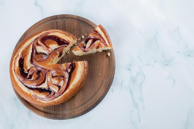 Cutting a slice of strawberry pie on wooden board.