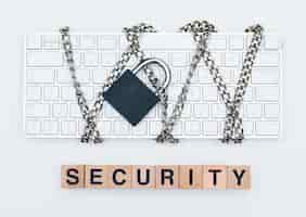 Free photo cyber safety concept with chain and padlock on keyboard, wooden cubes on white background flat lay.