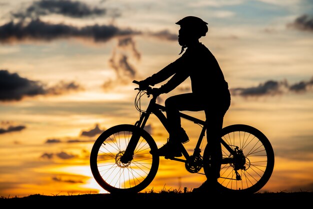 日没時のシルエットを休んでサイクリスト。アクティブな屋外スポーツコンセプト